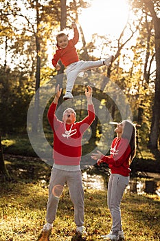 Portrait of a mother, father holds, throws up and spins the daughter on hands walking on nature on autumn day vacation. Mom, dad