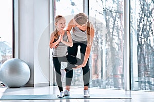 Portrait of mother gently teaching her small girl his first yoga notions careful near kids body helping daughter finished action photo