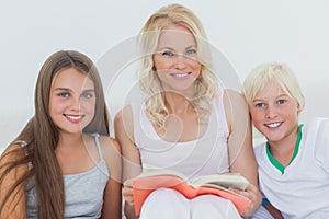 Portrait of mother holding a storybook to her children