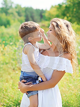 Portrait of mother hugging child son outdoors in summer