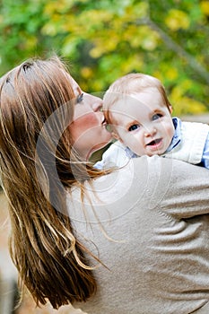 Portrait of mother kissing infant son outdoors