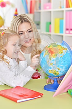 Portrait of mother with little daughter examine globe