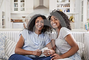 Portrait Of Mother Sitting With Teenage Daughter On Sofa