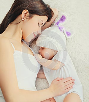 Portrait mother sleeping with her baby on bed at home, top view