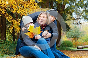 Portrait of a mother and son and daughter in autumn city park, happy people together, parent and children talking and smiling,