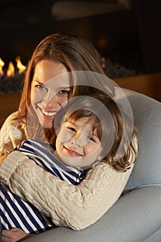 Portrait mother and son sitting in front of fire