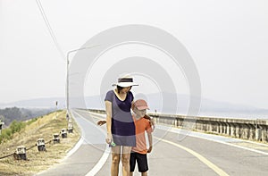Portrait of a mother and son walking on the street Background mountains and water at Krasiew dam ,Supanburi Thailand