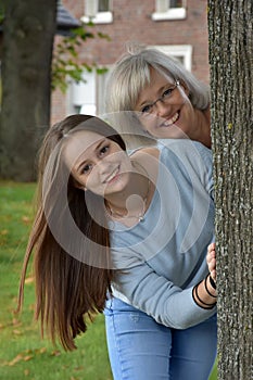 Portrait of mother and teenage daughter behind a tree