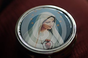 Portrait of Mother Virgin Mary on a cover of round metal rosary box. Pray rosary devotion concept. Catholic religion symbol.