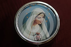 Portrait of Mother Virgin Mary on a cover of round metal rosary box. Pray rosary devotion concept. Catholic religion symbol.