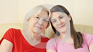 Portrait of mother and young daughter relaxing on sofa at home. Happy family enjoying time together