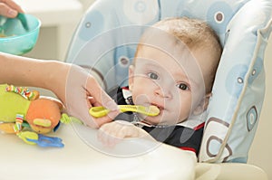 Portrait of mothers hand giving food in spoon to her baby boy