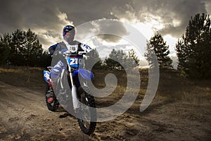 A portrait of motocross rider sitiing on the bike on the background of sunset