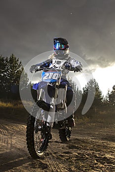 A portrait of motocross rider sitiing on the bike on the bakcground of sunset