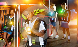 Portrait of mulatto tweenager boy with laser gun having fun on d