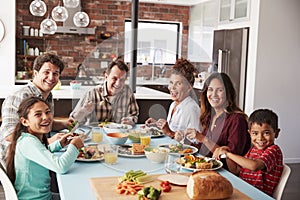 Portrait Of Multi Generation Family Enjoying Meal Around Table At Home Together