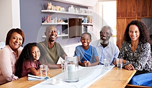 Portrait Of Multi-Generation Family Sitting Around Table At Home Enjoying Meal Together