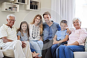 Portrait Of Multi Generation Family Sitting On Sofa At Home