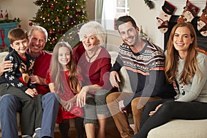 Portrait Of Multi Generation Family Sitting On Sofa In Lounge At Home On Christmas Day