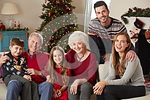 Portrait Of Multi Generation Family Sitting On Sofa In Lounge At Home On Christmas Day