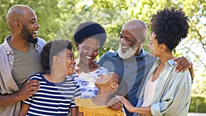 Portrait Of Multi-Generation Family Standing Outdoors In Garden Or Countryside Smiling At Camera