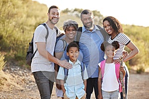 Portrait Of Multi Generation Family Wearing Backpacks Hiking In Countryside Together