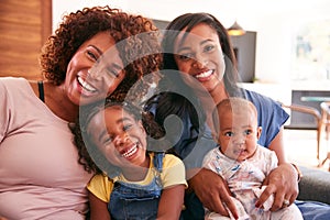 Portrait Of Multi-Generation Female African American Family Sitting On Sofa At Home