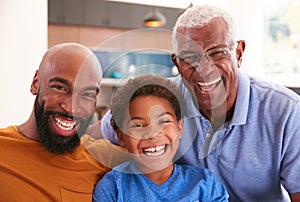 Portrait Of Multi-Generation Male African American Family Sitting On Sofa At Home