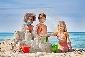 Happy friends making sandcastle on the beach