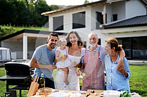 Portrait of multigeneration family outdoors on garden barbecue.