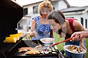 Portrait of multigeneration family outdoors on garden barbecue, grilling.