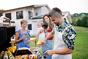 Portrait of multigeneration family outdoors on garden barbecue, grilling.