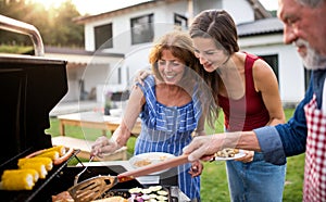 Portrait of multigeneration family outdoors on garden barbecue, grilling.