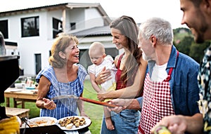 Portrait of multigeneration family outdoors on garden barbecue, grilling.