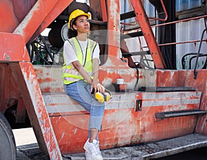 Portrait of multiracial woman industrial engineer in hard hat working at logistic container warehouse. Inspector or supervisor in