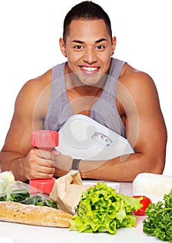 Portrait of muscle man posing in studio with food and dumbbells