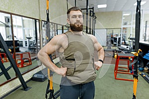 Portrait muscular caucasian bearded adult man in gym, dressed in bulletproof armored vest, military sport