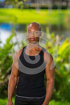 Portrait of a muscular fitness model posing in the park