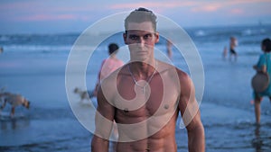 Portrait of muscular man with a naked torso on the beach at sunset.