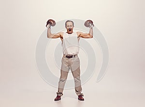 Portrait of muscular man in vintage clothes showing muscles in boxing gloves, posing isolated over grey studio