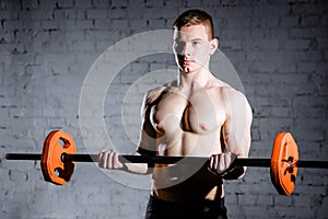 Portrait of a muscular man workout with barbell at gym.