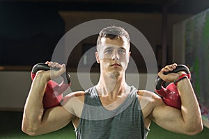 Portrait of muscular young man lifting weights at gym