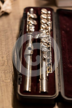 A portrait of a music case with a disassembled metal silver flute in it with valves to play notes. the musical instrument will