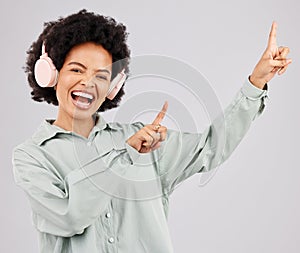 Portrait, music headphones and black woman pointing up in studio isolated on a white background mockup or advertising