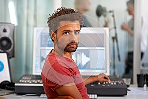 Portrait, music and a man producer in a recording studio mixing audio with a sound desk. Computer, tech or media with a