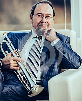 Portrait of a musician with a trumpet sitting in a chair, on the