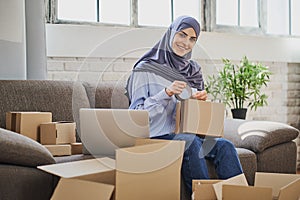 Portrait of a Muslim business woman packaging orders into cardboard boxes