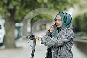 Portrait of a muslim girl in a green hijab with a scooter on the street