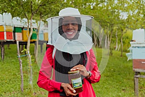 Portrait of a Muslim investitor in the beekeeping department of a honey farm holding a jar of honey in her hand photo