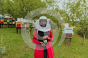 Portrait of a Muslim investitor in the beekeeping department of a honey farm holding a jar of honey in her hand photo